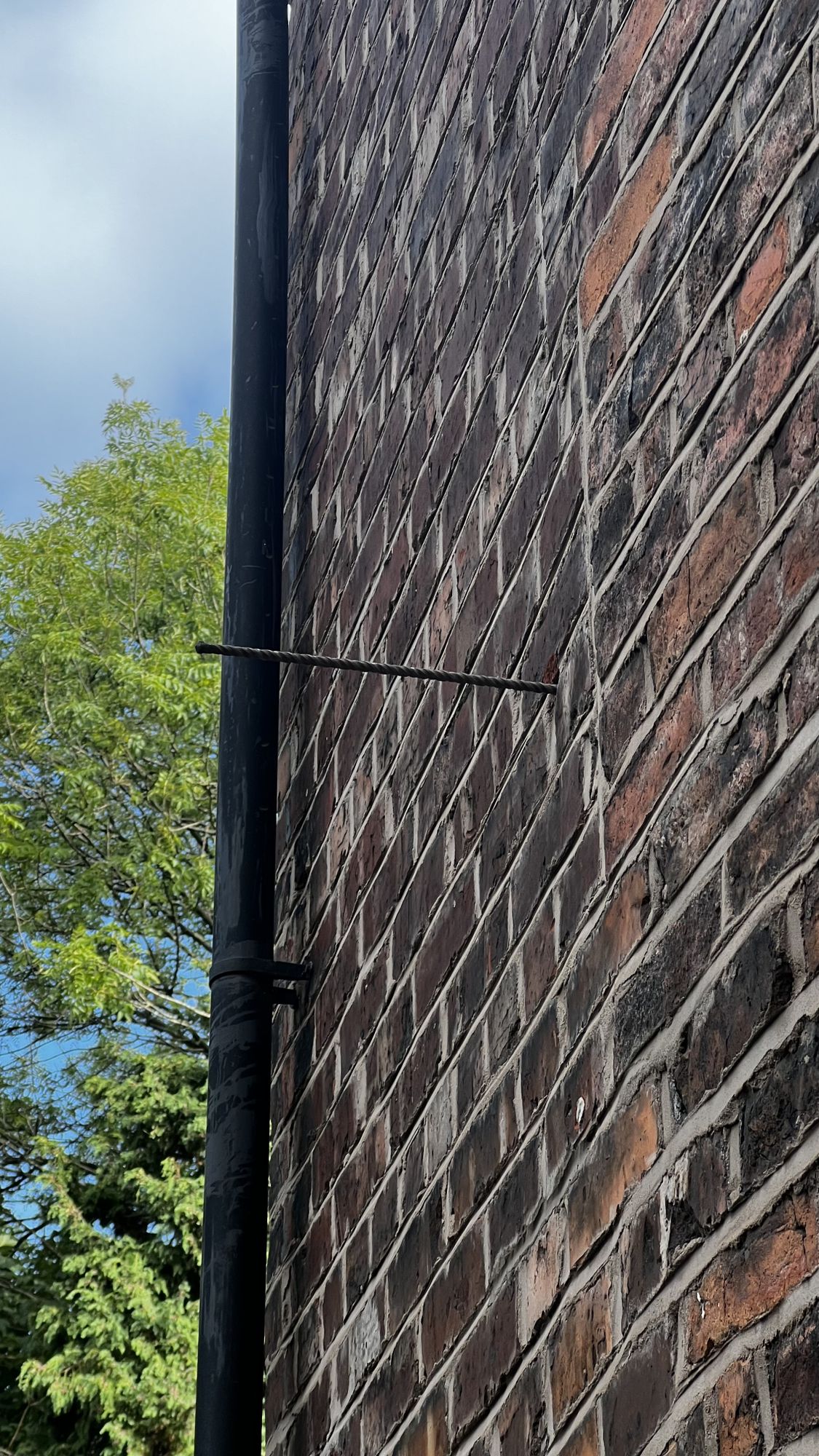 Network cable clipped along brickwork beside a downpipe